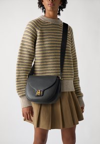 Borsa a spalla in pelle nera con forma curva, accessoriata in oro e con finitura testurizzata. La tracolla presenta un motivo con logo.