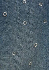 Denim fabric in medium blue featuring silver metal eyelets evenly spaced across the surface, creating a textured look.