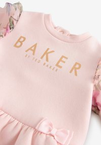 Rosa Sweatshirt-Kleid mit transparenten, blumenförmigen Puffärmeln, goldfarbenem "BAKER by TED BAKER"-Logo und einem kleinen rosa Schleifenakzent in der Taille.