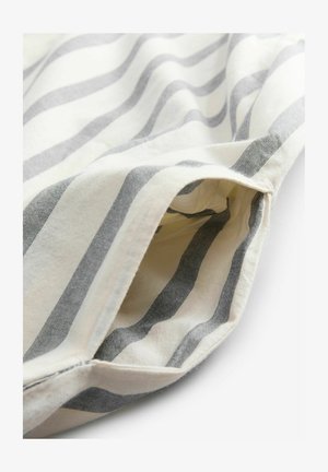 Tissu en coton avec des rayures ondulées grises et blanches. L'image montre un bord replié avec un détail de poche. Surface texturée avec des coutures visibles.