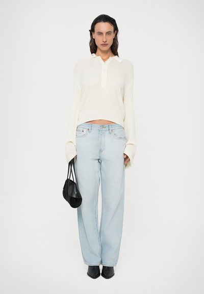 Cremefarvet, ribbet striktrøje med lange ærmer og krave, parret med lyseblå straight-leg jeans. Sort taske og spidse sorte sko inkluderet.