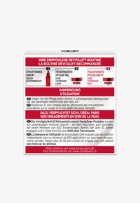 Röd och vit hudvårdsbox som visar produktnamn, instruktioner och åtaganden på tyska och franska. Tydlig, läsbar textlayout.