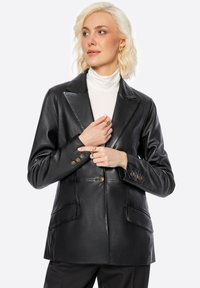 Zwart leren blazer met een gladde textuur, sluiting met één knop en twee voorkruiszakken. Bevat brede revers en knopen in goudkleur.