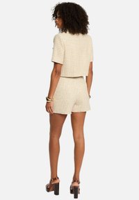 Ensemble en crochet composé d'un haut court à manches courtes et d'un short assorti, tous deux dans un motif pied-de-poule crème et beige.