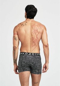 Boxer-briefs noirs avec un motif de circuits, dotés d'une large taille élastique portant l'étiquette "FUNK DADDY". Des tatouages visibles couvrent le dos du modèle.