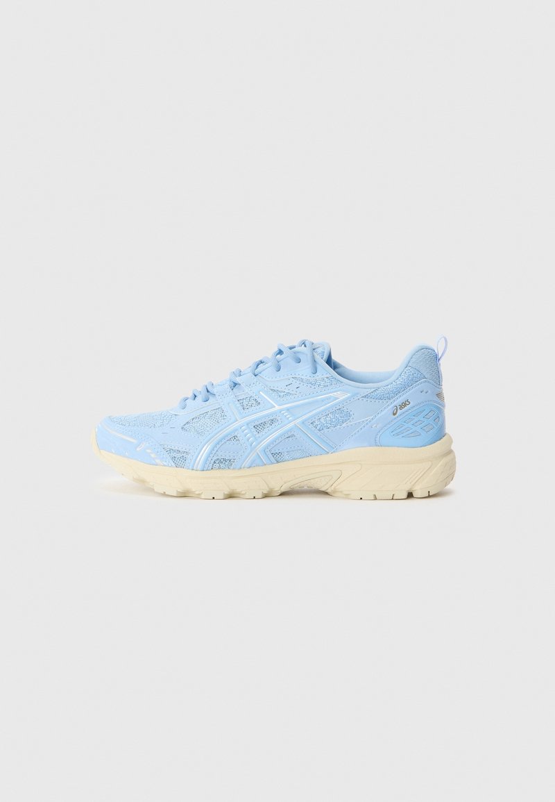 Chaussure de course ASICS bleu clair avec tige en mesh, surcouches à motifs, semelle beige, fermeture à lacets et languette au talon.