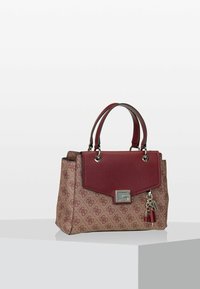 Borsa a tracolla marrone a fantasia con patta in pelle rossa, hardware in argento, doppi manici e un charm decorativo sul lato. Materiali testurizzati utilizzati.