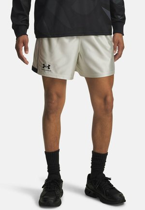 Hvide sportsshort med en glat tekstur, sort logo og accenter, parret med sorte sko og ribbede sorte sokker.