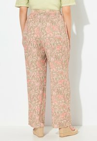 Pantaloni leggeri e stampati in beige con motivi di animali rosa; vita elastica; taglio a gamba larga; tessuto testurizzato; abbinati a scarpe color sabbia.