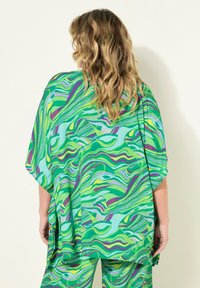 Grön och blå abstrakt-mönstrad kaftan med en lös, flödande passform och fladdermusärmar, gjord av lättviktig tyg. Accentfärger i lila och gult.