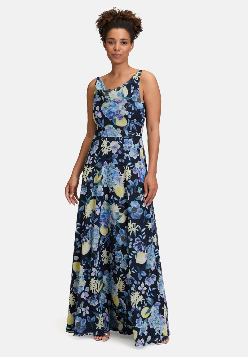 Robe longue avec un motif floral dans des nuances de bleu, jaune et vert sur un fond bleu marine foncé. Présente un design sans manches et un corsage ajusté.