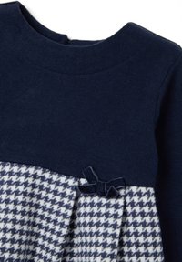 Abito blu navy con parte superiore semplice e gonna a motivo houndstooth. Presenta un dettaglio in velluto a forma di fiocco in vita. Materiale in maglia morbido.