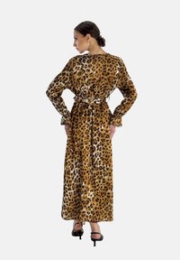 Leopardmönstrad maxiklänning med långa ärmar, insnörd midja och utsvängd silhuett. Tillverkad av mjukt tyg med svarta och bruna djurmönster.