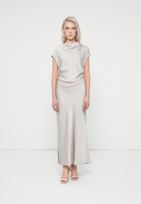 Robe en satin gris clair avec un décolleté drapé, des manches courtes et une silhouette ajustée. Présente une fente latérale et arrive aux chevilles.