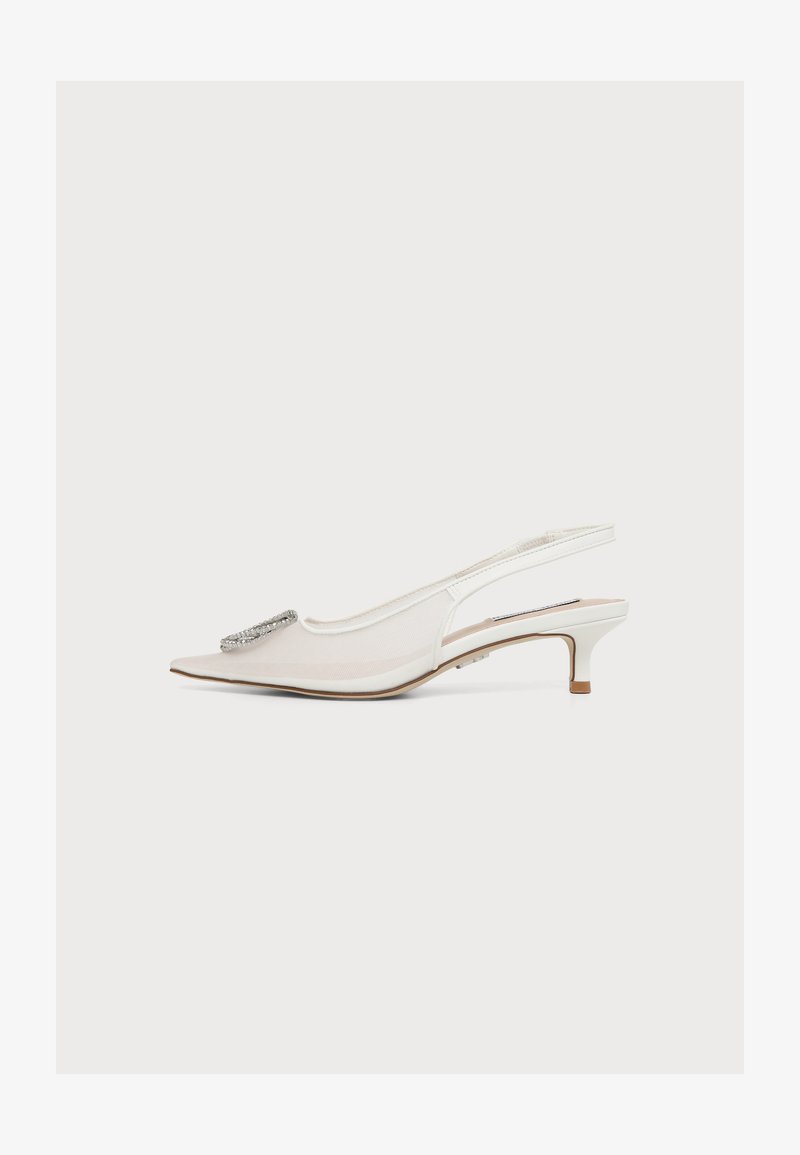 Chaussure blanche à talon kitten avec bride slingback, bout pointu et boucle argentée décorative à l'avant, vue de côté sur un fond uni.