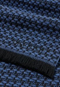 Gewebter Schal in Blau und Schwarz mit einem strukturierten Hahnentrittmuster; mit einem schwarzen Fransenrand und eingeprägtem Markenlogo.