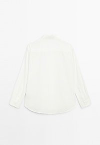 Camicia bianca a maniche lunghe, tessuto morbido, colletto classico, polsini con bottone, orlo curvo, senza motivi o decorazioni visibili sul retro.