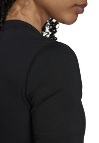 Black athletic shirt featuring a fitted design, textured fabric, and visible stitching along the shoulder and neck areas.