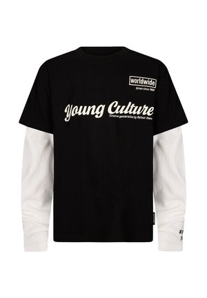 Maglietta nera a maniche corte indossata sopra una maglia a maniche lunghe bianca, con il testo "Young Culture" e "worldwide Driven since 1989" sul davanti.