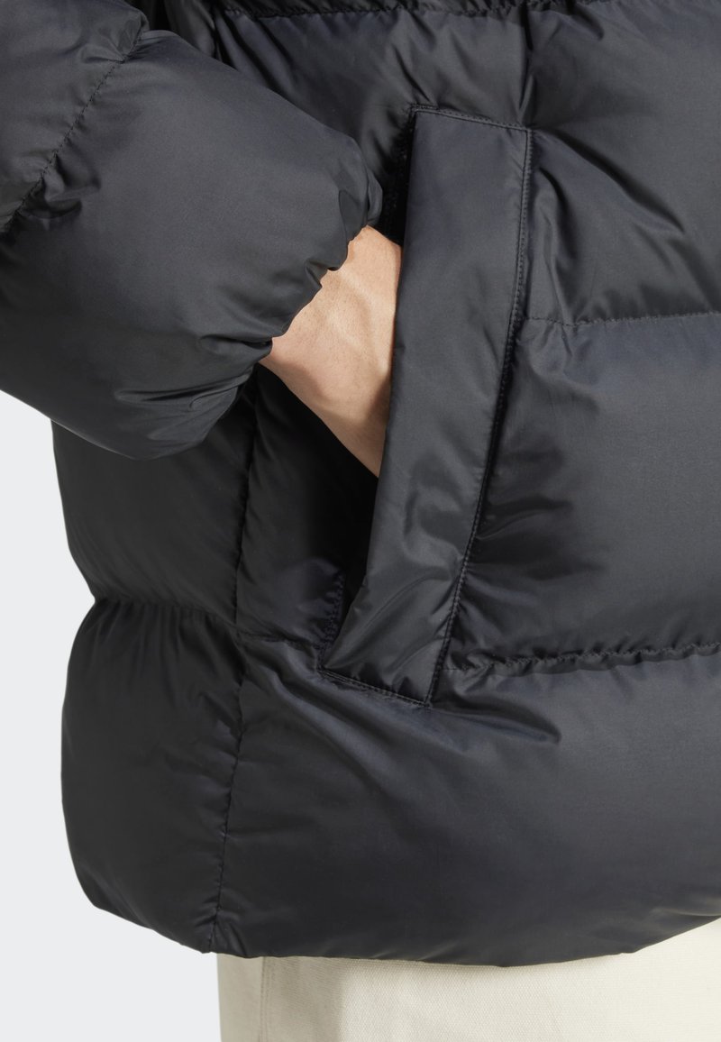 Schwarze Pufferjacke mit matter Oberfläche, ausgestattet mit einer Seitentasche und gerafftem Futter für Isolation. Geschmeidige Textur und elegantes Design.