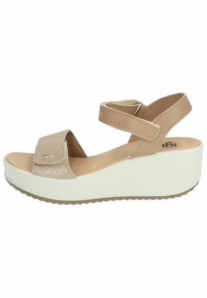 Beige sandals with a textured accent strap, adjustable ankle straps, and a white wedge sole featuring a patterned base for traction.