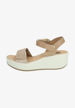Sandali beige con una cinturino accentuato testurizzato, cinghie regolabili alla caviglia e una suola a cuneo bianca con una base patterned per la trazione.