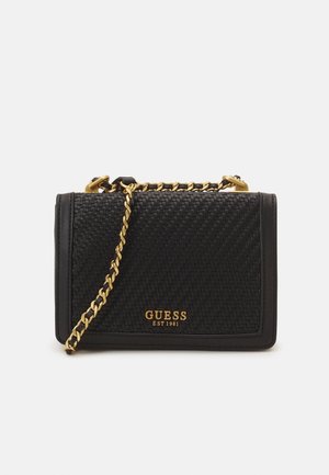 Sac à bandoulière en cuir tissé noir avec une chaîne dorée et un logo doré "GUESS EST 1981" sur le devant.