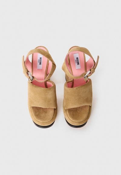 Beige mockaskin plattformsandaler med öppen tå, korsningsdesign och spänne. Rosa innerfoder och svart sula.