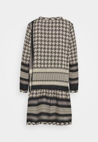 Vestido de manga larga con patrón de cuadrícula en beige y negro y patrones a rayas, que presenta diseños en forma de chevrón y acanalados sobre un fondo blanco.