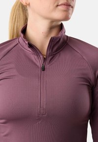 Maglia a maniche lunghe con zip a quarto in mauve scuro, realizzata in tessuto morbido ed elasticizzato, con un dettaglio del logo a forma di montagna in rilievo vicino all'orlo.