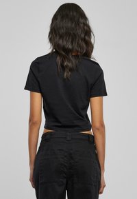 Svart cropped t-skjorte med korte ermer, laget av bomull, med et enkelt design uten synlige mønstre eller aksenter.