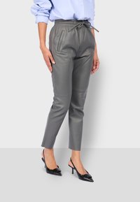 Šedé kožené kalhoty s elastickým pasem a šňůrkou, obsahující boční kapsy a zúžený střih. Hladká textura a přiléhavý design.
