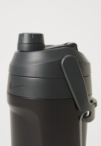 Zwarte plastic waterfles met een gestructureerde grip, een schroefdeksel en een zijhandvat. Voorzien van een opvallend Nike-logo op de fles.