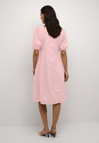 Pink and white striped dress with puff sleeves, a fitted bodice, and a flared skirt. Features button closure and soft fabric texture.