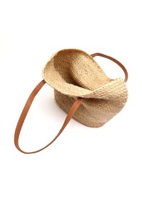 Sac en paille tressée avec un design décontracté, doté de poignées en cuir beige clair et d'une texture douce. Couleur neutre et forme minimaliste.