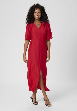 Robe rouge, longueur genou, avec un décolleté en V et de courtes manches évasées. Dotée d'une fente à l'avant, fabriquée à partir d'un tissu léger.