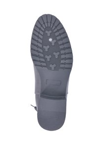 Semelle de botte en caoutchouc noir avec un motif de bande de roulement strié pour une meilleure adhérence, de forme arrondie et avec une surface lisse près du talon.
