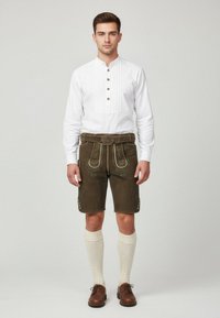 White long-sleeve shirt with button placket, paired with brown leather shorts featuring ornate stitching and silver hardware. Knee-high cream socks and brown shoes.