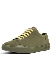Chaussure en daim vert avec lacets jaunes, bout arrondi et semelle en caoutchouc mouchetée. Présente un détail de couture et un logo sur le côté.