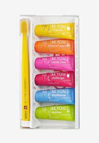 Ensemble de dentifrice Curaprox avec six tubes colorés en rose, orange, vert, bleu, jaune et violet, plus une brosse à dents à poils souples jaune.
