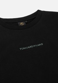 Zwarte katoenen t-shirt met "TOMORROWLAND" in lichtblauw geborduurd. Ronde halslijn en zachte textuur. Standaard pasvorm.