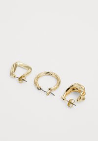 Tři páry náušnic zlaté barvy ve tvaru kruhu: jeden čtvercový, jeden spirálový a jeden texturovaný v organickém tvaru, se zapínáním na tyčku.