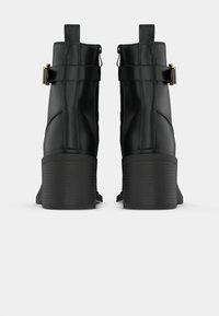 Μαύρες μπότες στον αστράγαλο με λεία επιφάνεια, ψη�λό τετράγωνο τακούνι, πλευρικές ζώνες και θηλάκια στην κορυφή. Σχεδιασμένες για μια μοντέρνα εμφάνιση.