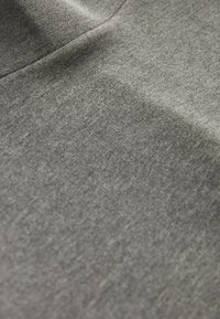 Gros plan sur un tissu gris doux avec une couture visible et une texture subtile.