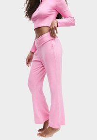 Roze geribbelde lounge-set met een cropped lange mouw top en flared broek met een brede tailleband en zijsplitten. Zachte textuur.