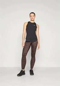 Fekete ujjatlan felső burgundi leggingssel, amely sötét leopárdmintás. A modell fekete sportcipőt visel, egyenesen áll.