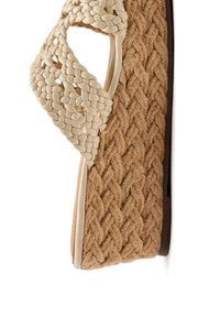 Sandale compensée en fibre naturelle tressée de couleur beige, avec une lanière tressée crème et une semelle intermédiaire texturée pour une meilleure adhérence.
