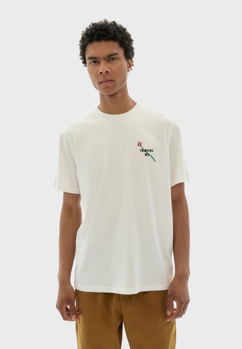 Witte katoenen t-shirt met een klein bloemenontwerp en tekst, ronde hals, korte mouwen en een ontspannen pasvorm. Accenten zijn onder andere borduursels.