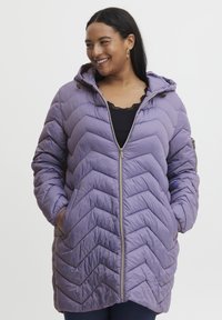 Fialová bunda s kapucňou a so zapínaním na zips, so vzorom v tvare chevronu. Materiál vyzerá mäkký a prešívaný, má bočné vrecká.