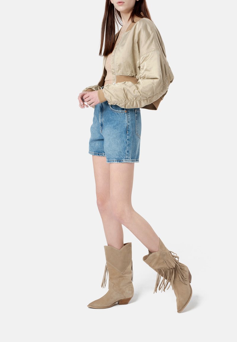 Kerged nahast cowboy saapad frantsi/detailiga, teravate varbaga ja madalate kontsadega, millele on lisatud lühike bomber-jakk ja teksashortsid.